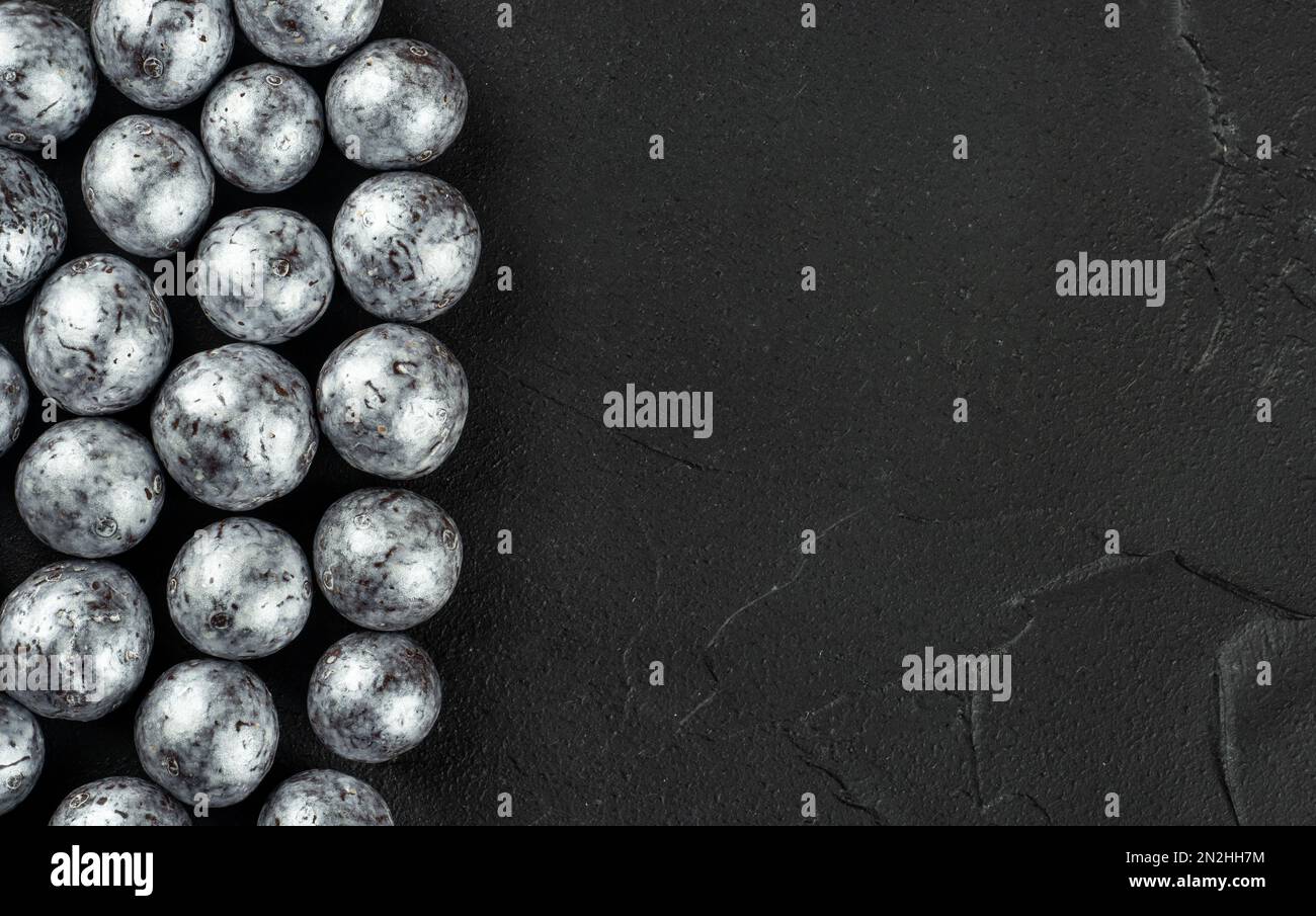 Silberne Bonbons Haselnüsse in Schokolade auf dunklem Betonhintergrund verstreut, Kopierraum. Stockfoto