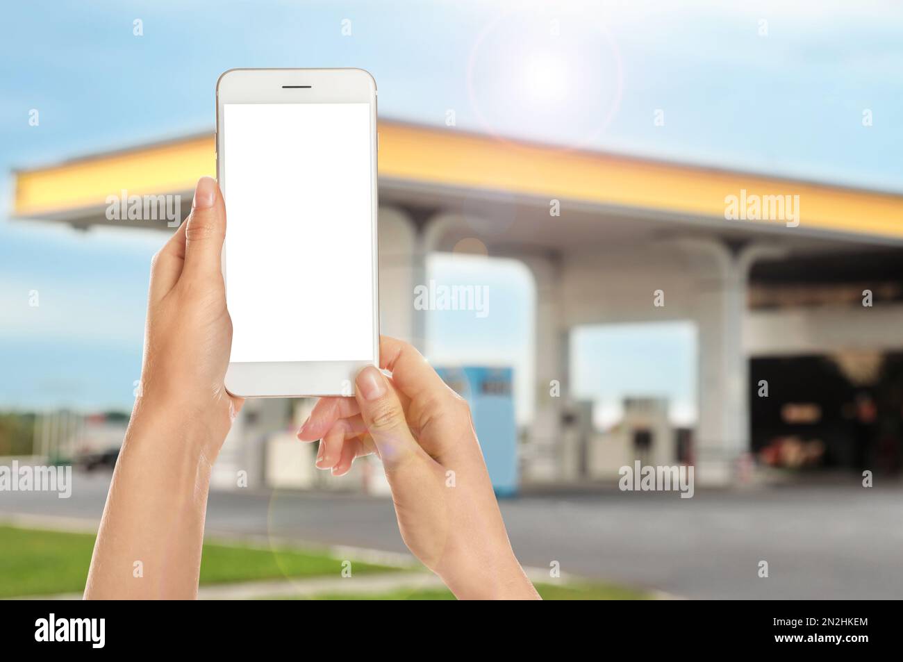 Frau, die für das Betanken per Smartphone an der Tankstelle bezahlt, Nahaufnahme. Gerät mit leerem Bildschirm Stockfoto