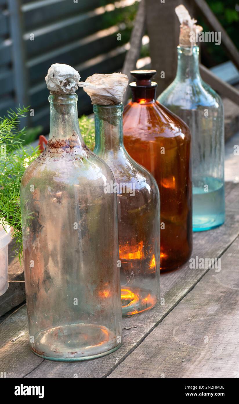 Mehrere alte und schmutzige Glasflaschen auf einem Holztisch draußen im Dorf. Stockfoto