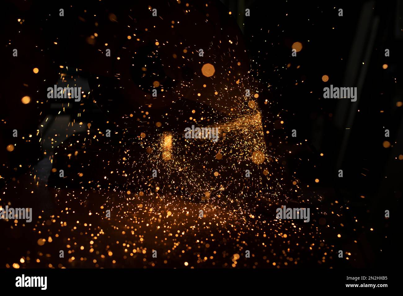 Funken aus Metall. Stahlsägen. Industrieller Hintergrund. Viele helle Funken auf dunklem Hintergrund. Stockfoto