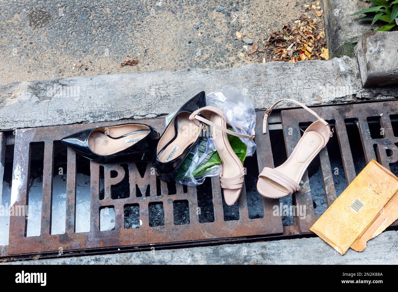 Zwei Paar entsorgte, kaputte Frauenschuhe auf einem Abfluss in Ho-Chi-Minh-Stadt, Vietnam Stockfoto