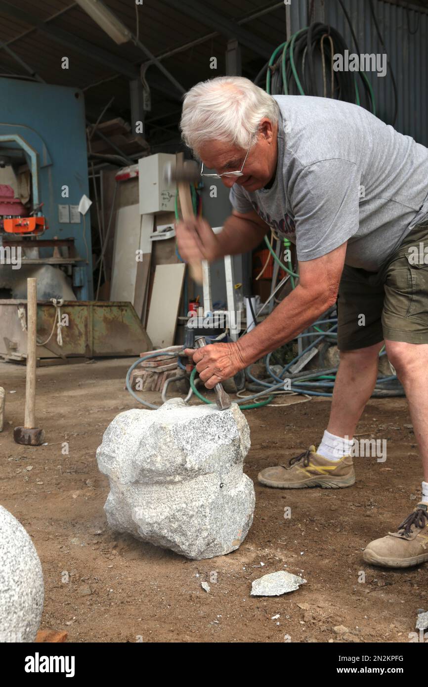25. Mai 2017 - Toskana, Italien : erfahrener Marmorarbeiter, der aus dem Rohstein eine Marmorkugel mit einem Steinmetz und Hammer baut. Detail des Materials Stockfoto