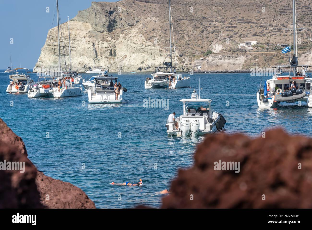 Red Beach, Santorin, Griechenland - August 2022 : Boote und Katamarane in einer Bucht am Red Beach in Santorin Stockfoto