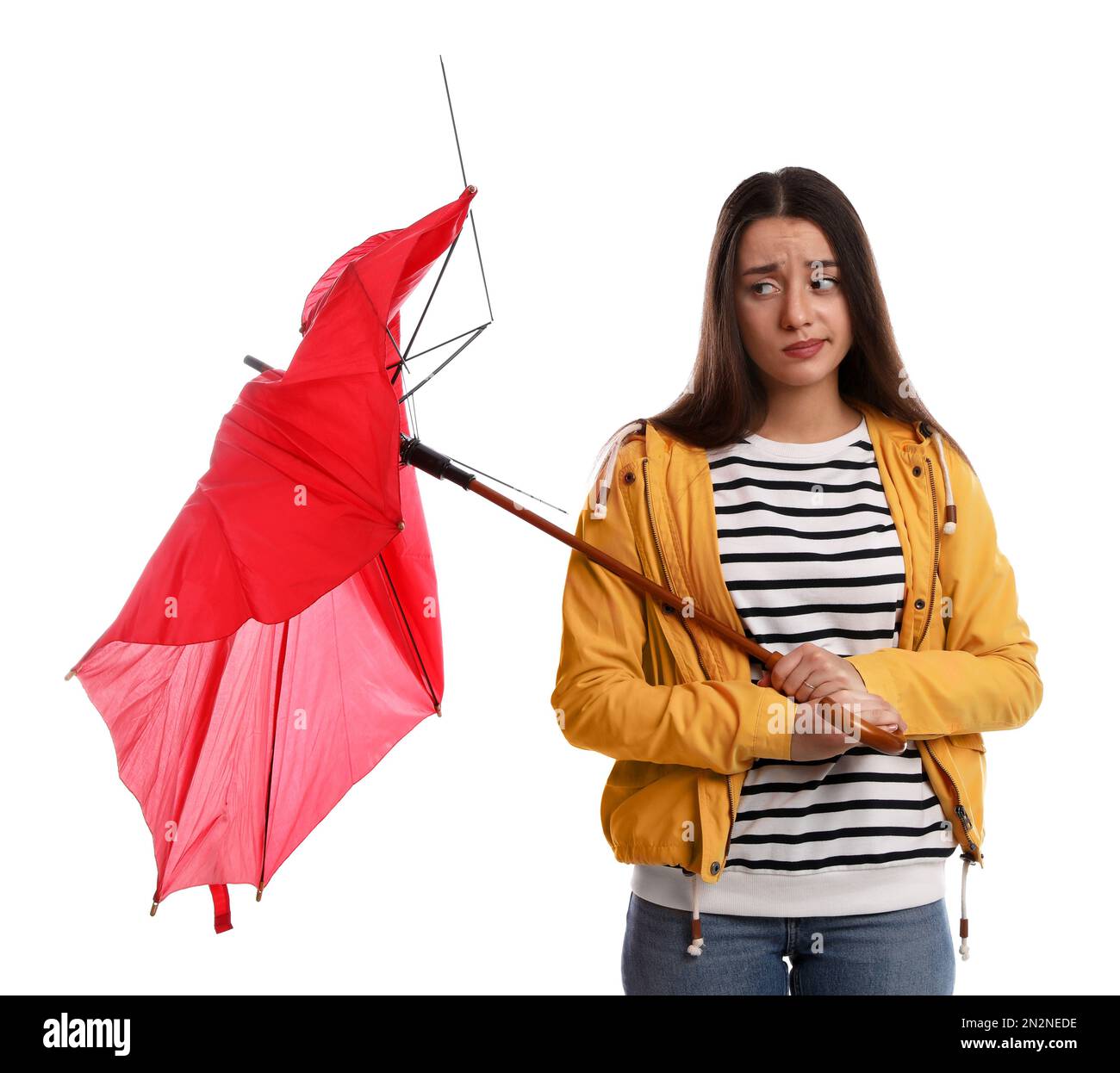 Emotionale Frau mit einem Regenschirm, der durch Windstoß auf weißem Hintergrund zerbrochen wurde Stockfoto
