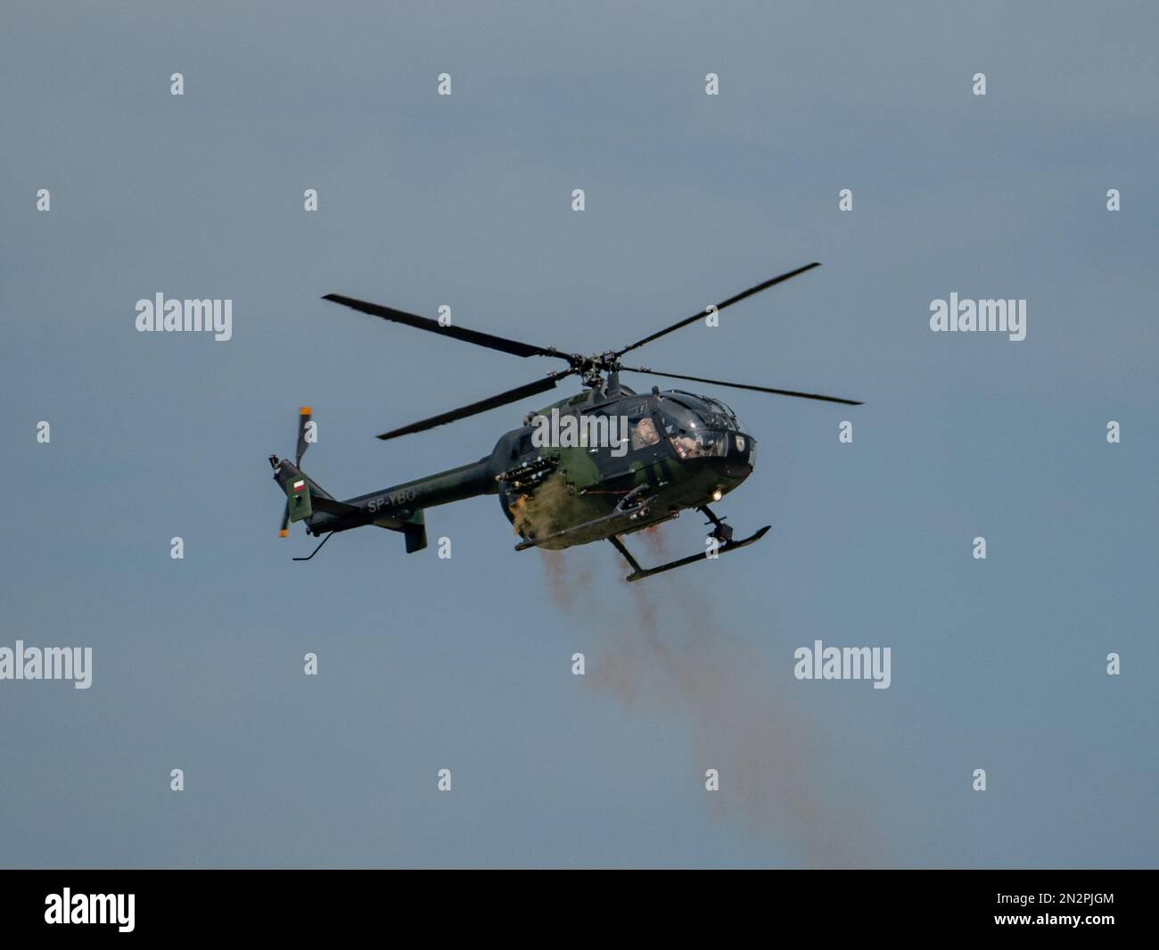 Eine Nahaufnahme des MBB BO105-Hubschraubers, der bei einer Flugschau in der Slowakei Farbe am Himmel freisetzt Stockfoto