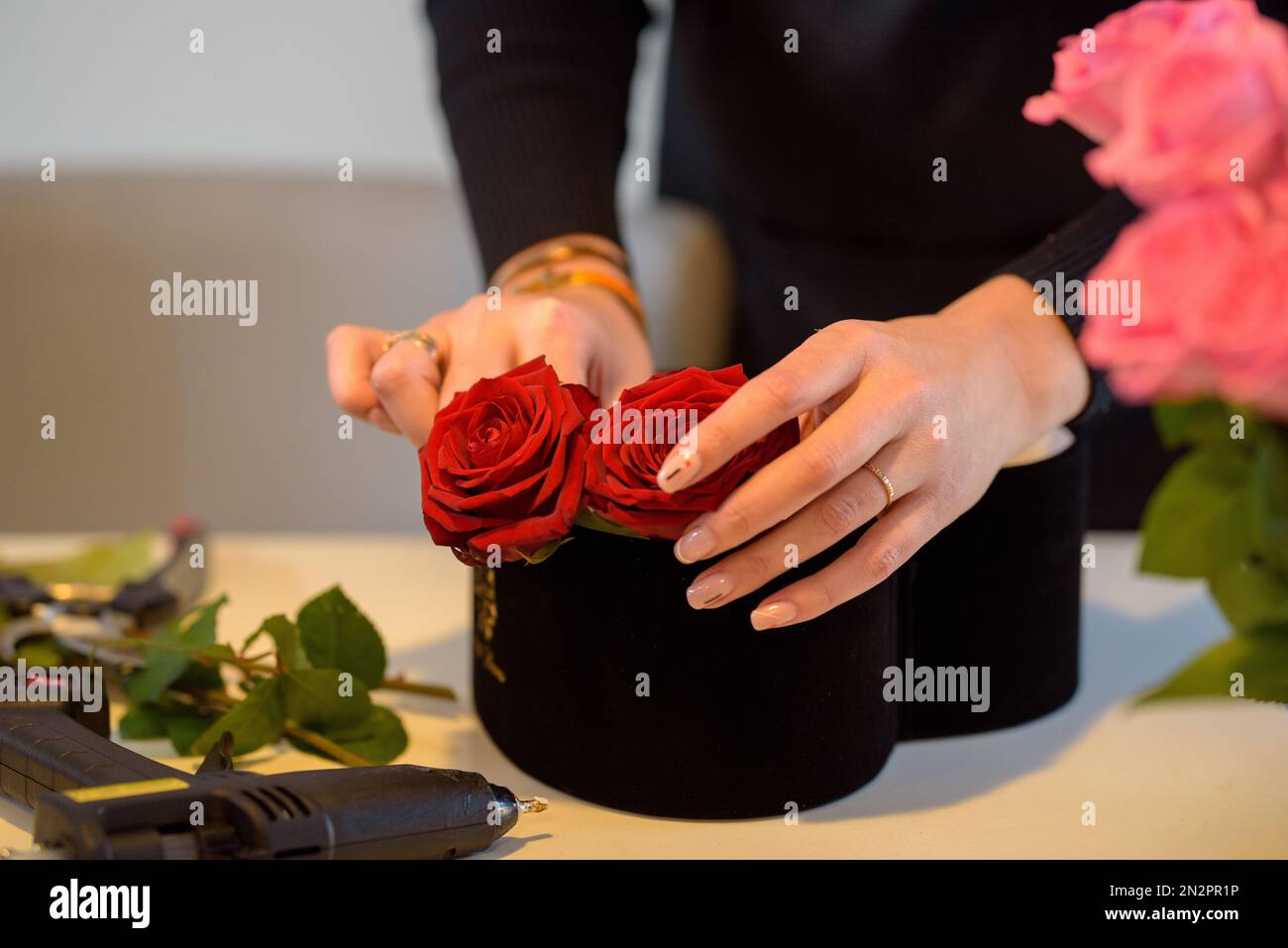 Nahaufnahme einer Frau, die am Valentinstag ein Blumenarrangement mit roten Rosen macht Stockfoto