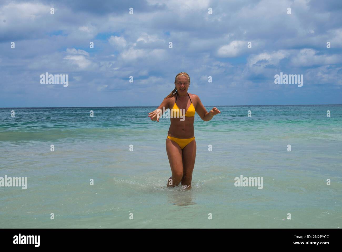 Lächelnde Frau in einem Bikini, die aus dem Meer geht, Beau Vallon Beach, Mahe Island, Seychellen Stockfoto
