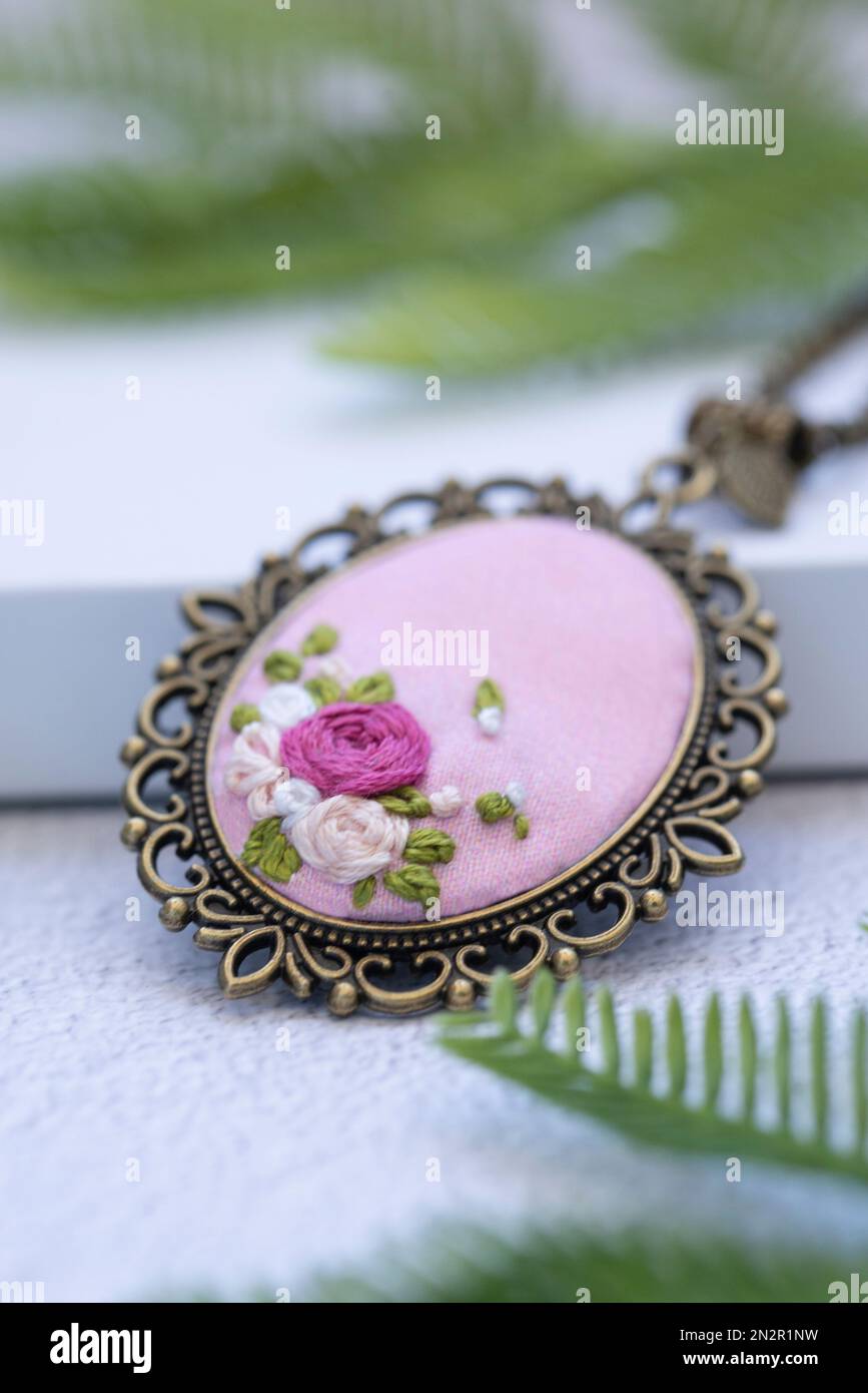 Nahaufnahme einer von Hand gestickten Halskette auf einer weißen Geschenkbox mit Tannenzweigen Stockfoto