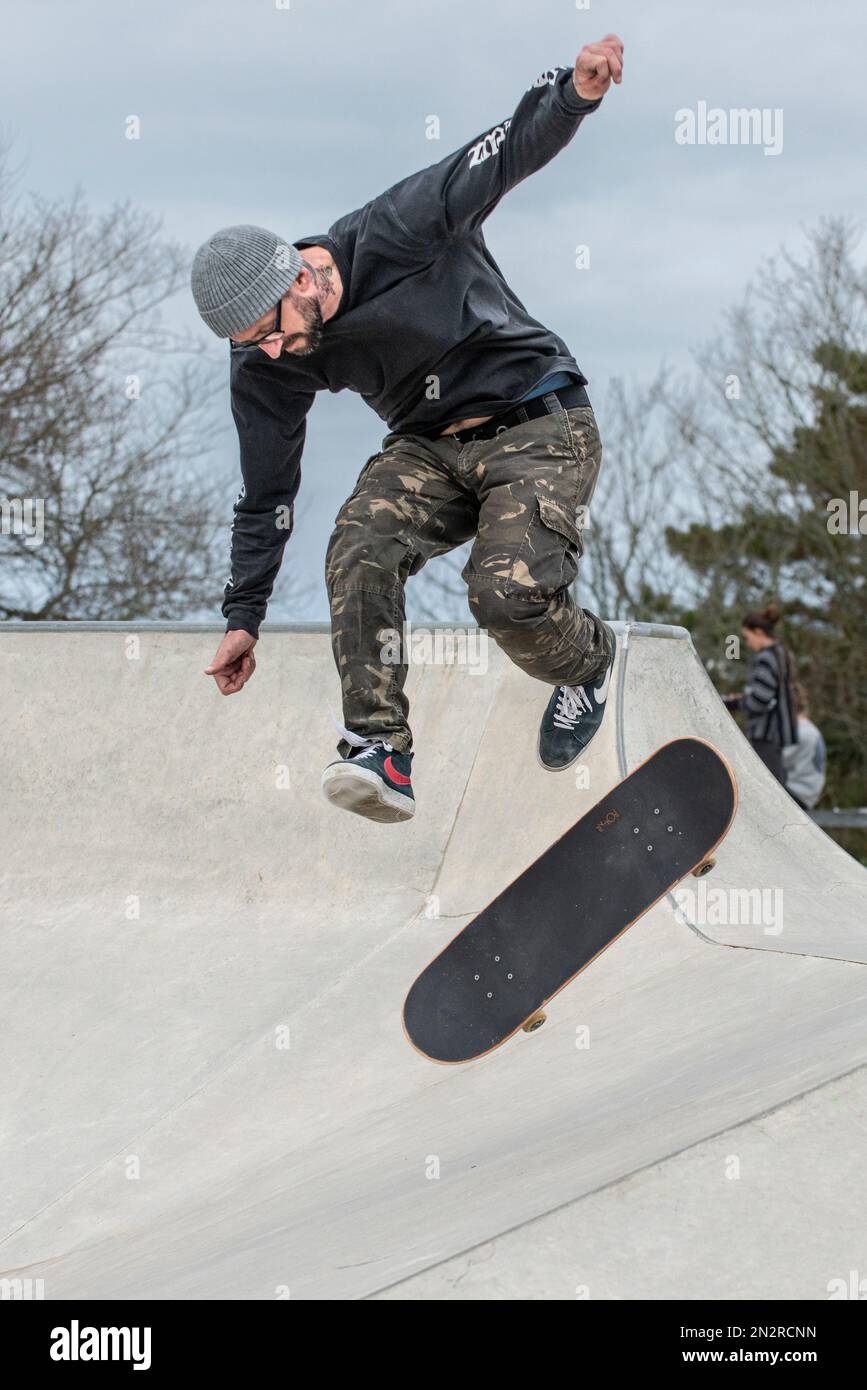 Ein reifer männlicher Skateboarder, der einen Trick im Newquay Concrete Waves Skatepark in Newquay in Cornwall in Großbritannien macht. Stockfoto