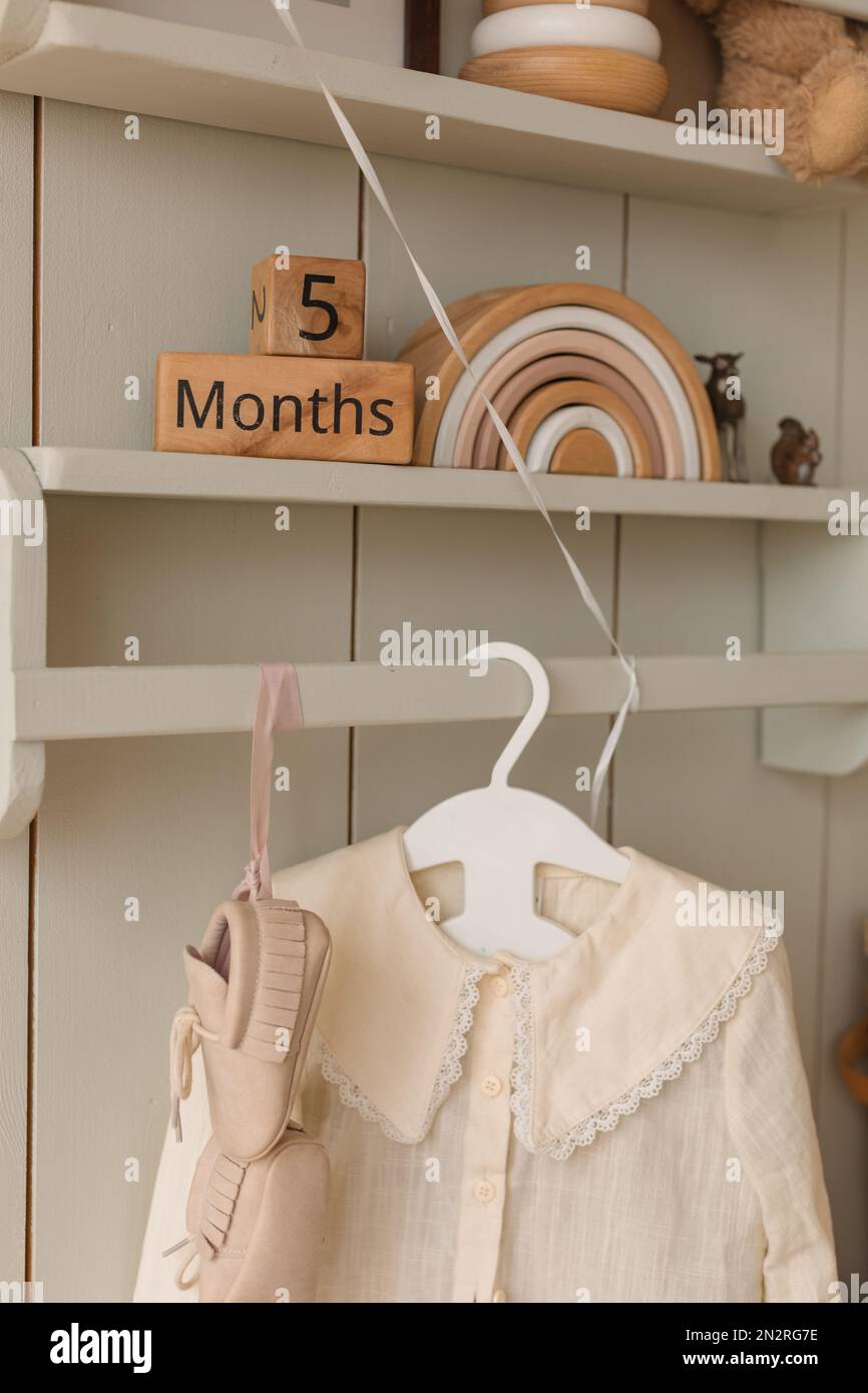 Nahaufnahme von Kinderbekleidung, die an einem Kleiderschrank hängt, mit Kinderspielzeug auf Regalen Stockfoto