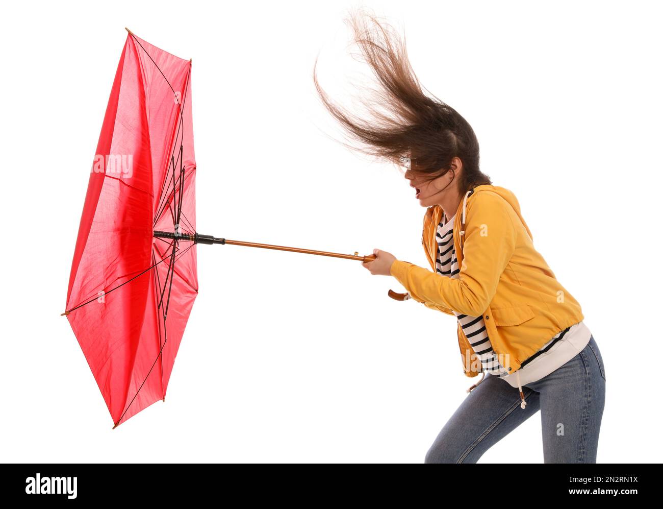 Eine Frau mit Regenschirm, die in Windböen auf weißem Hintergrund gefangen war Stockfoto