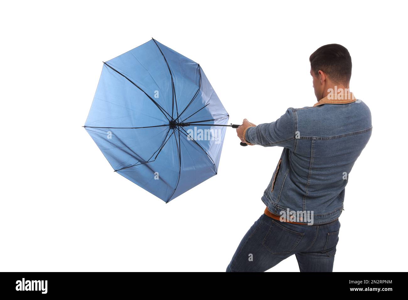 Ein Mann mit Regenschirm, der von Windböen auf weißem Hintergrund gefangen wurde Stockfoto