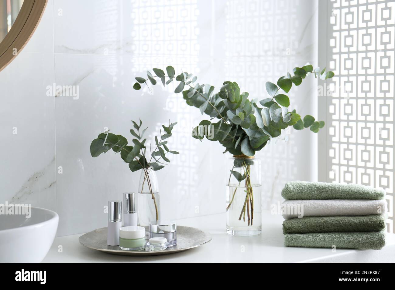 Frische Eukalyptusäste und Kosmetikprodukte auf der Arbeitsfläche im Badezimmer Stockfoto