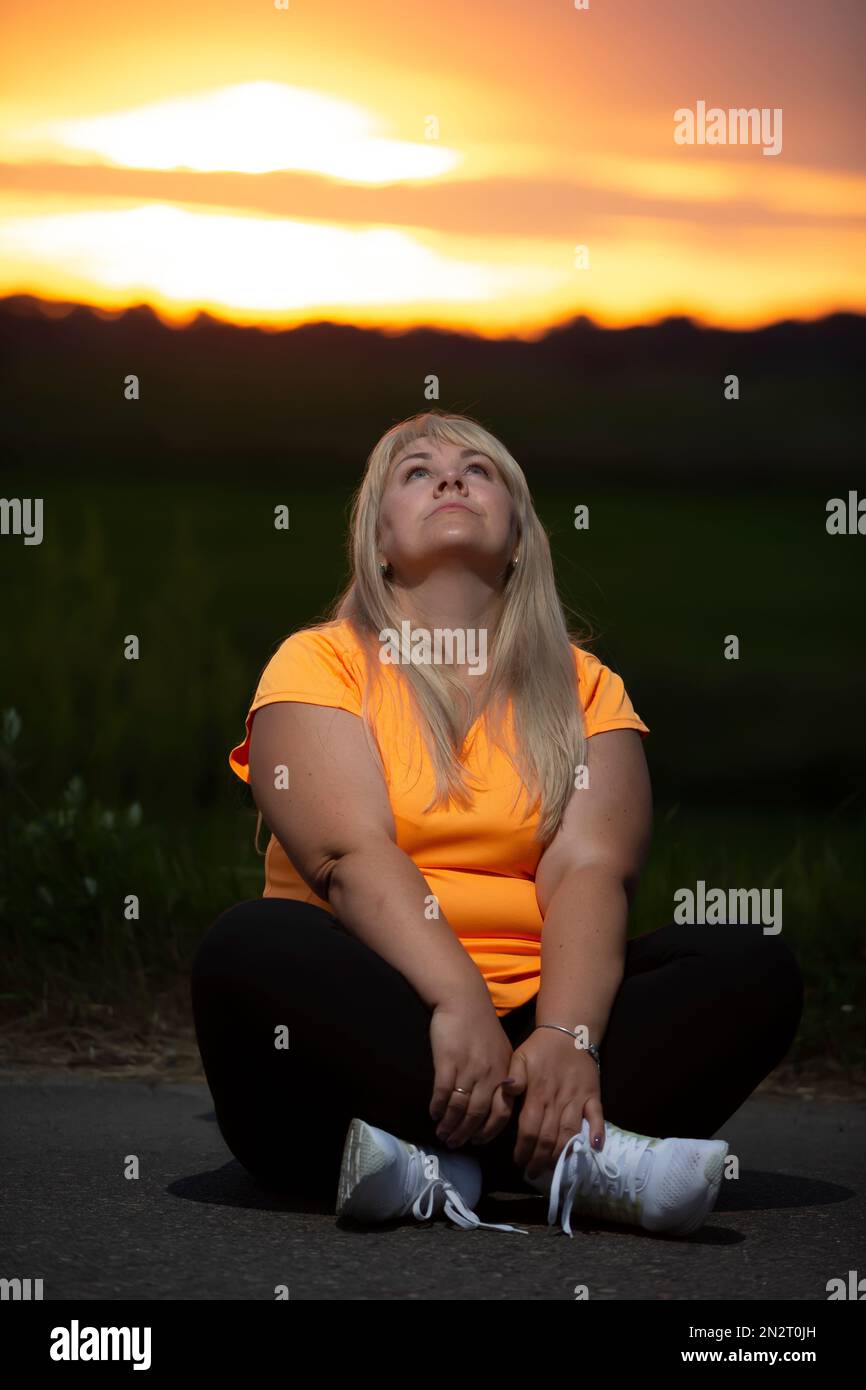 Porträt einer europäischen Frau mittleren Alters in einem Trainingsanzug, posiert für die Kamera, entspannend. Aufgeregt übergewichtige Frau im trendigen Trainingsanzug nach e ruhen Stockfoto