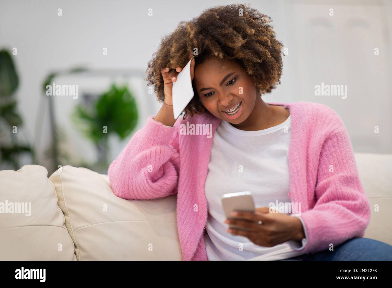 Verwirrte afroamerikanische Frau, die auf den Telefonbildschirm schaut, Kopierraum Stockfoto