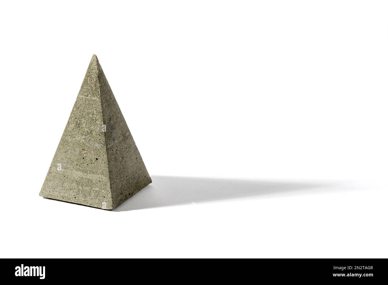 Graue pyramidenförmige Skulptur aus Zementguss mit geometrischem Schatten auf weißem Hintergrund Stockfoto