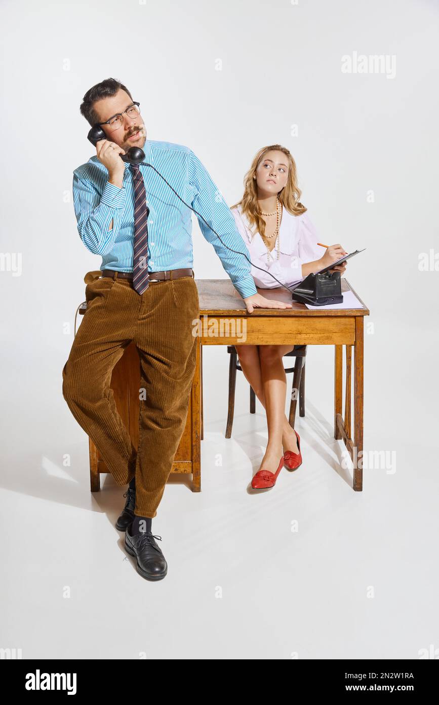 Geschäftsmann telefoniert und Frau, persönliche Assistentin macht Notizen vor grauem Hintergrund. Geschäftskonzept, Beschäftigung, Arbeit Stockfoto