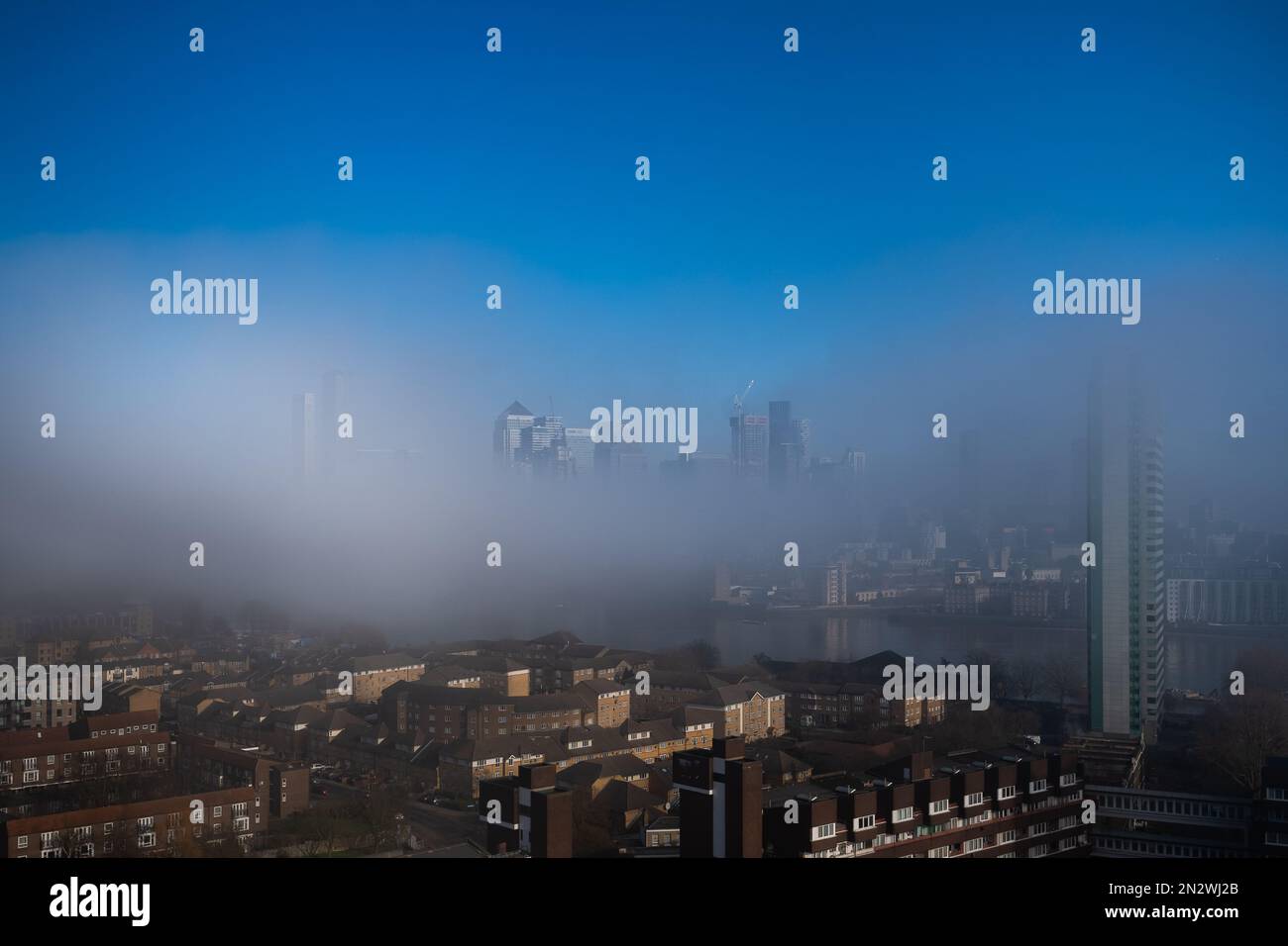 London, Großbritannien. 7. Februar 2023 UK Weather: Die Gebäude des Gewerbeparks Canary Wharf im Osten Londons werden allmählich wieder auftauchen, wenn der starke Morgennebel langsam über die Themse steigt. Kredit: Guy Corbishley/Alamy Live News Stockfoto