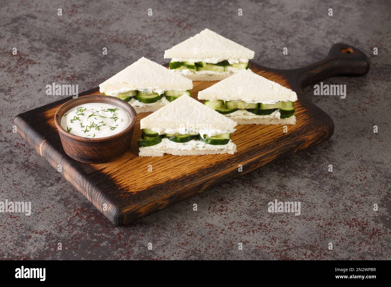 Hausgemachte englische Sandwiches mit frischer Gurke, Dill und Frischkäse, Nahaufnahme auf einem Holzbrett auf dem Tisch. Horizontal Stockfoto