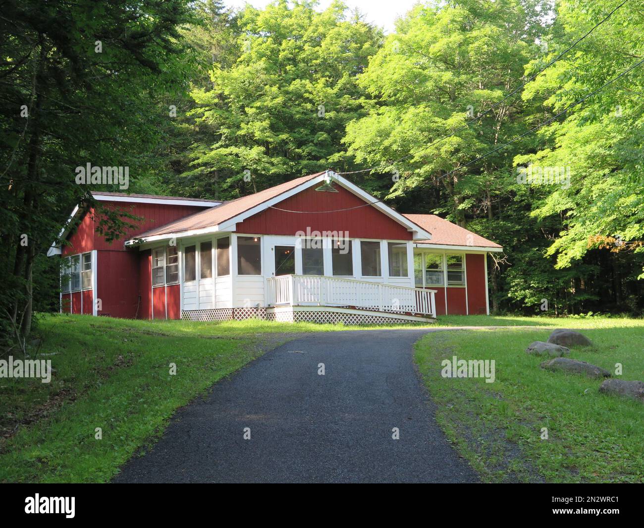 Die Ferienhütte ist rot und weiß gestrichen, inmitten von Waldwäldern, Pfad Stockfoto