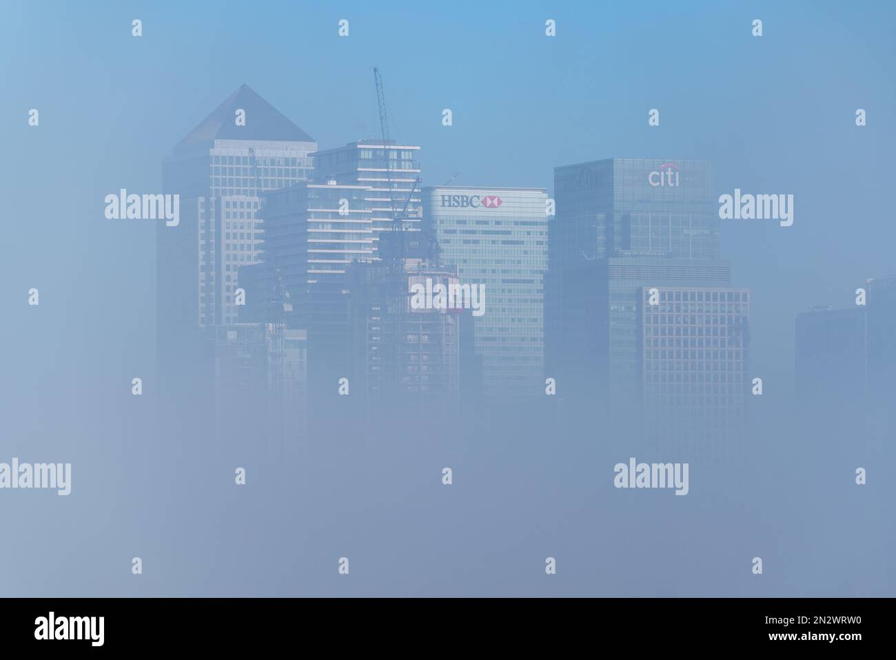 London, Großbritannien. 7. Februar 2023 UK Weather: Die Gebäude des Gewerbeparks Canary Wharf im Osten Londons werden allmählich wieder auftauchen, wenn der starke Morgennebel langsam über die Themse steigt. Kredit: Guy Corbishley/Alamy Live News Stockfoto
