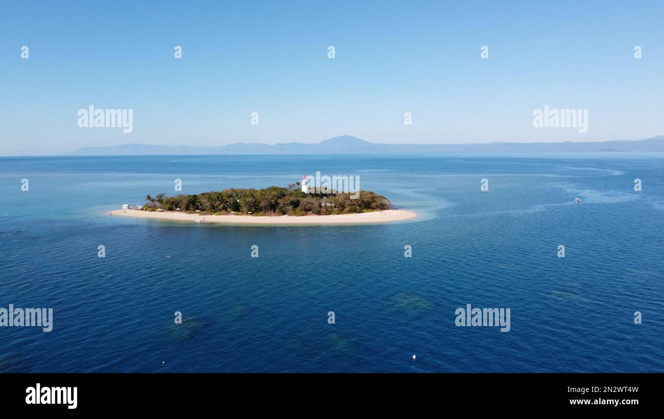 Niedrige Inseln. Eine tropische Insel mit Palmen und einem Leuchtturm, umgeben von einem Riff. Stockfoto
