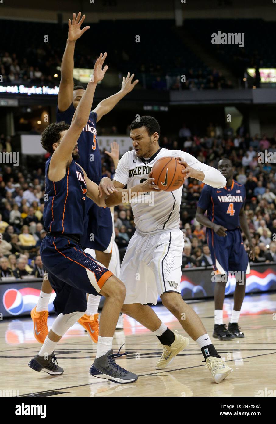 Wake Forest's Devin Thomas, right, drives against Virginia's Anthony Gill, left, and Darion Atkins, back, during the first half of an NCAA college basketball game in Winston-Salem, N.C., Wednesday, Feb. 25, 2015. (AP Photo/Chuck Burton) Stockfoto