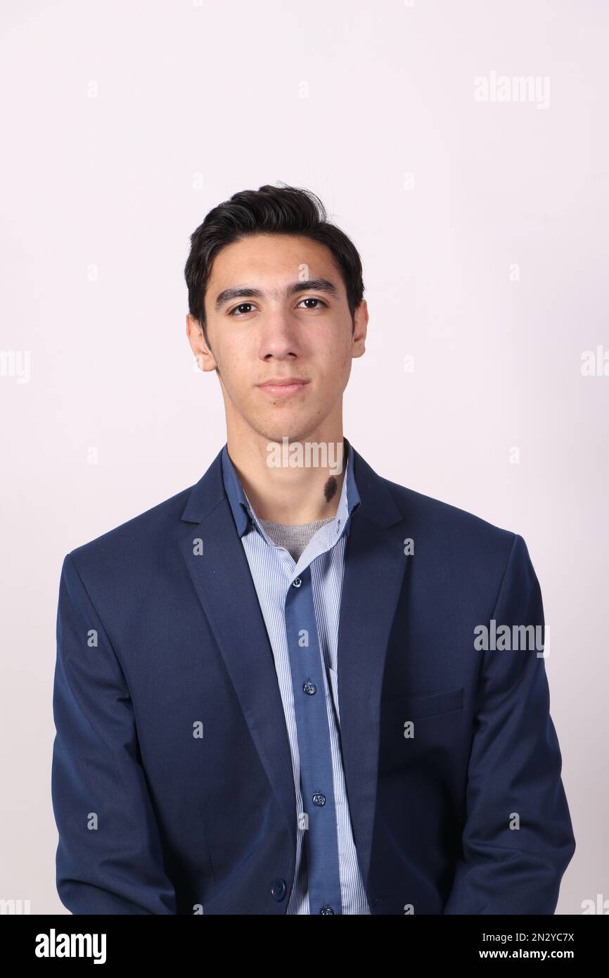 Ein Teenager, der einen marineblauen Anzug und ein blaues Hemd mit weißem Hintergrund trägt und in die Kamera schaut. Stockfoto