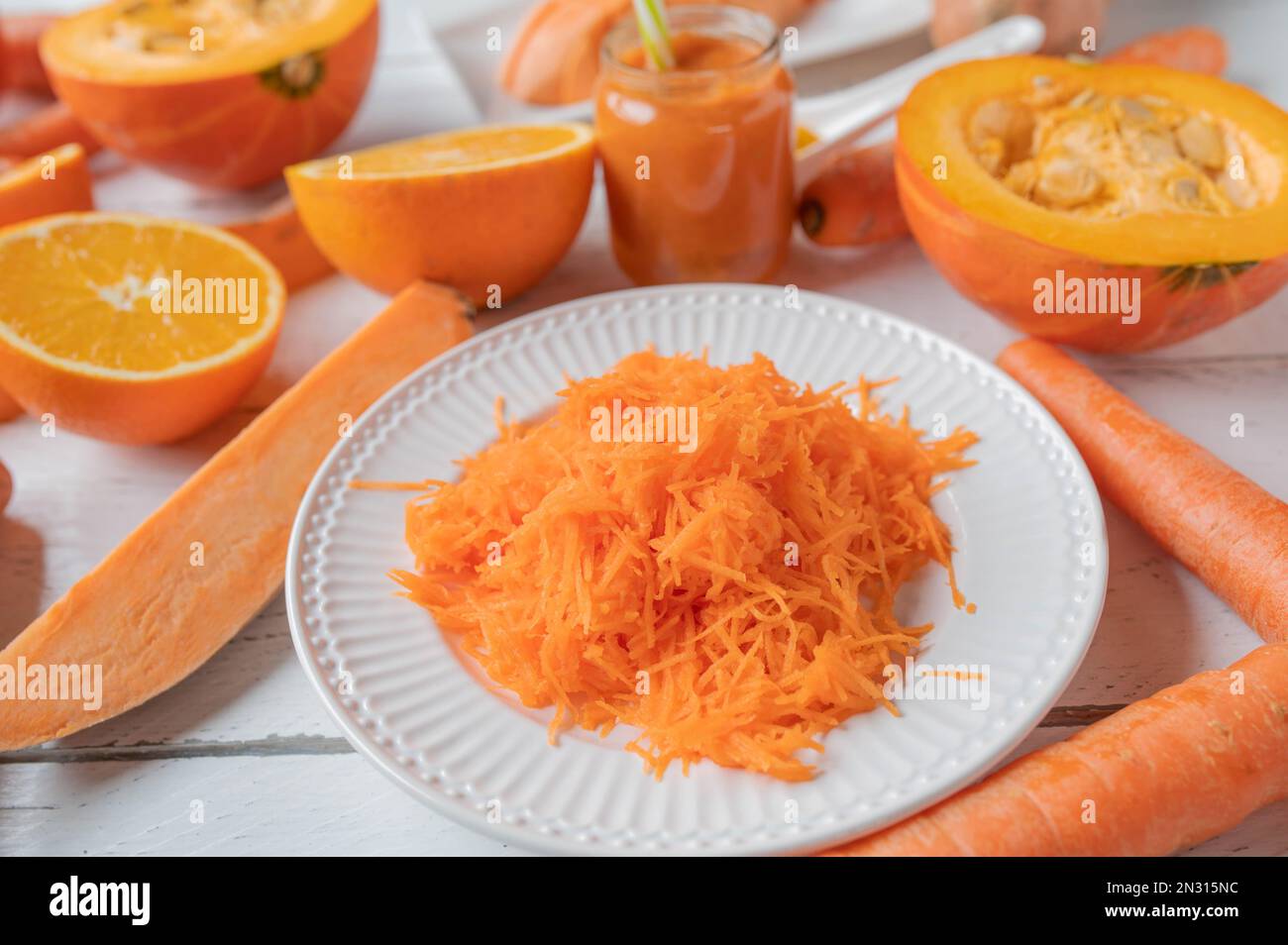 Buntes Gemüse und Früchte mit Orangenfarben auf weißem Hintergrund. Nahaufnahme und Vorderansicht Stockfoto