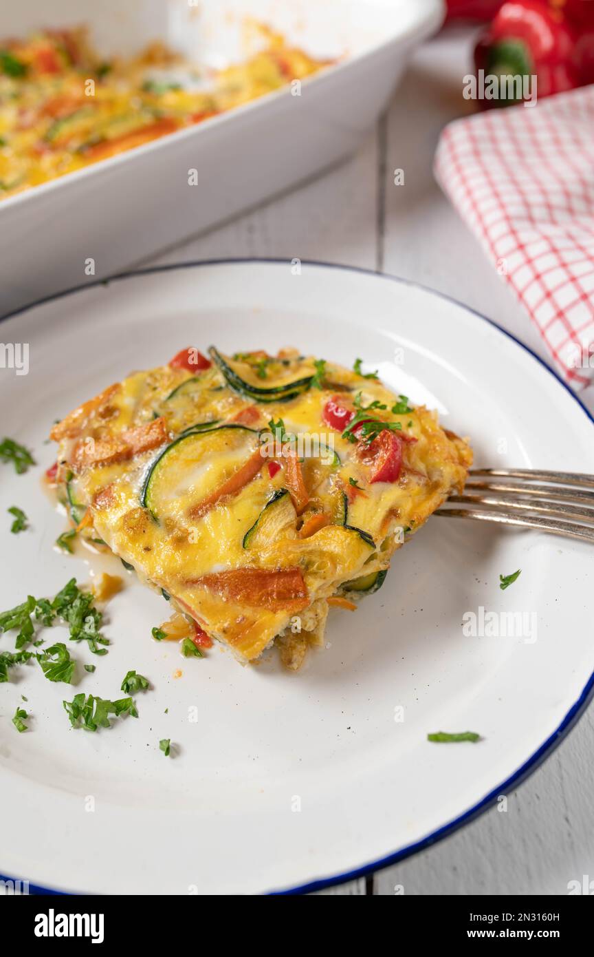 Frittata mit Zucchini, Tomaten, Karotten, Zwiebeln und Paprika auf einem Teller Stockfoto