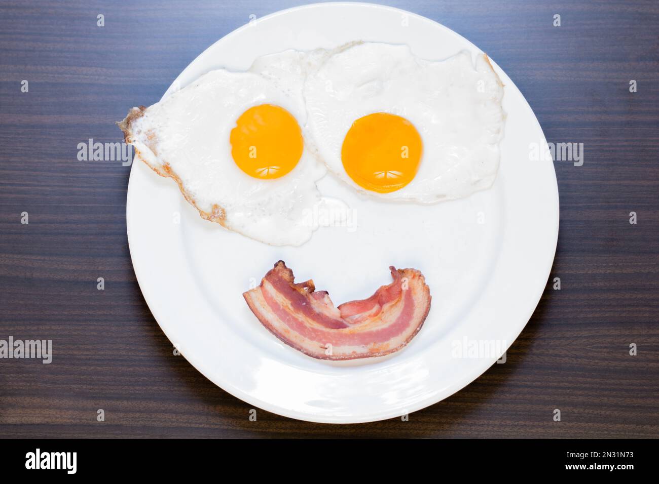 Lächelnde Spiegeleier mit Speck Stockfoto