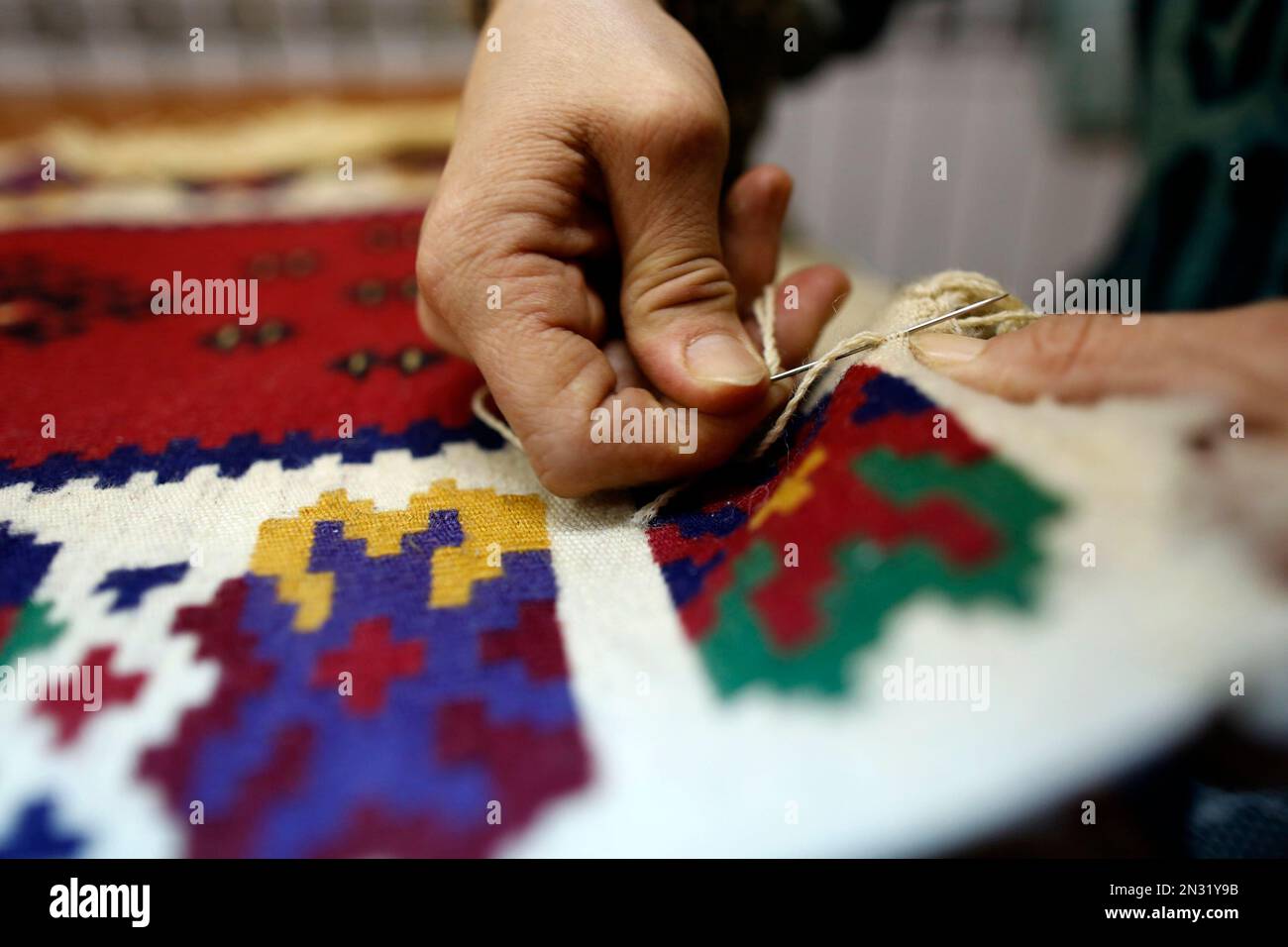 In this photo taken Monday, Jan. 26, 2015, a carpet weaver repairs an old Pirot carpet in the eastern Serbian town of Pirot. The carpet weaving in Pirot _ done only by local women and according to special rules _ is a centuries old tradition that is part of Serbia’s rich national heritage and one of the oldest Balkan crafts. (AP Photo/Darko Vojinovic) Stockfoto