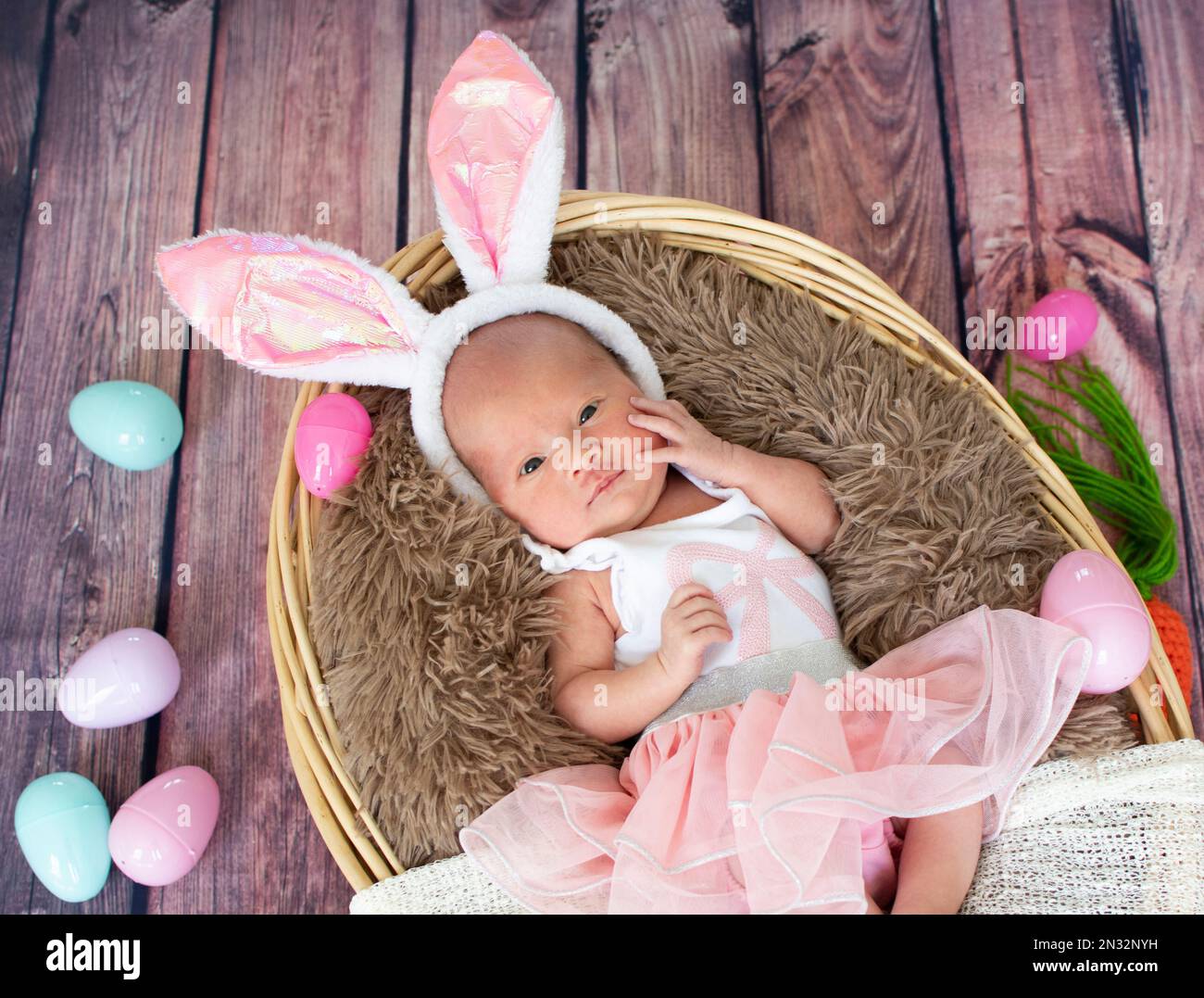 Neugeborenes Mädchen im Osterkorb mit Kaninchenohren. Stockfoto