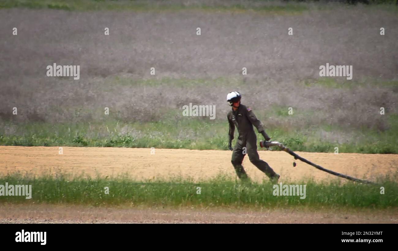 Ein Helikopter-Crewman in der Marine-Expeditionstruppe schleppt die Kraftstoffleitung zu einem Hubschrauber, um dort während einer Trainingsübung auf einer unbefestigten Landebahn zu tanken. Stockfoto