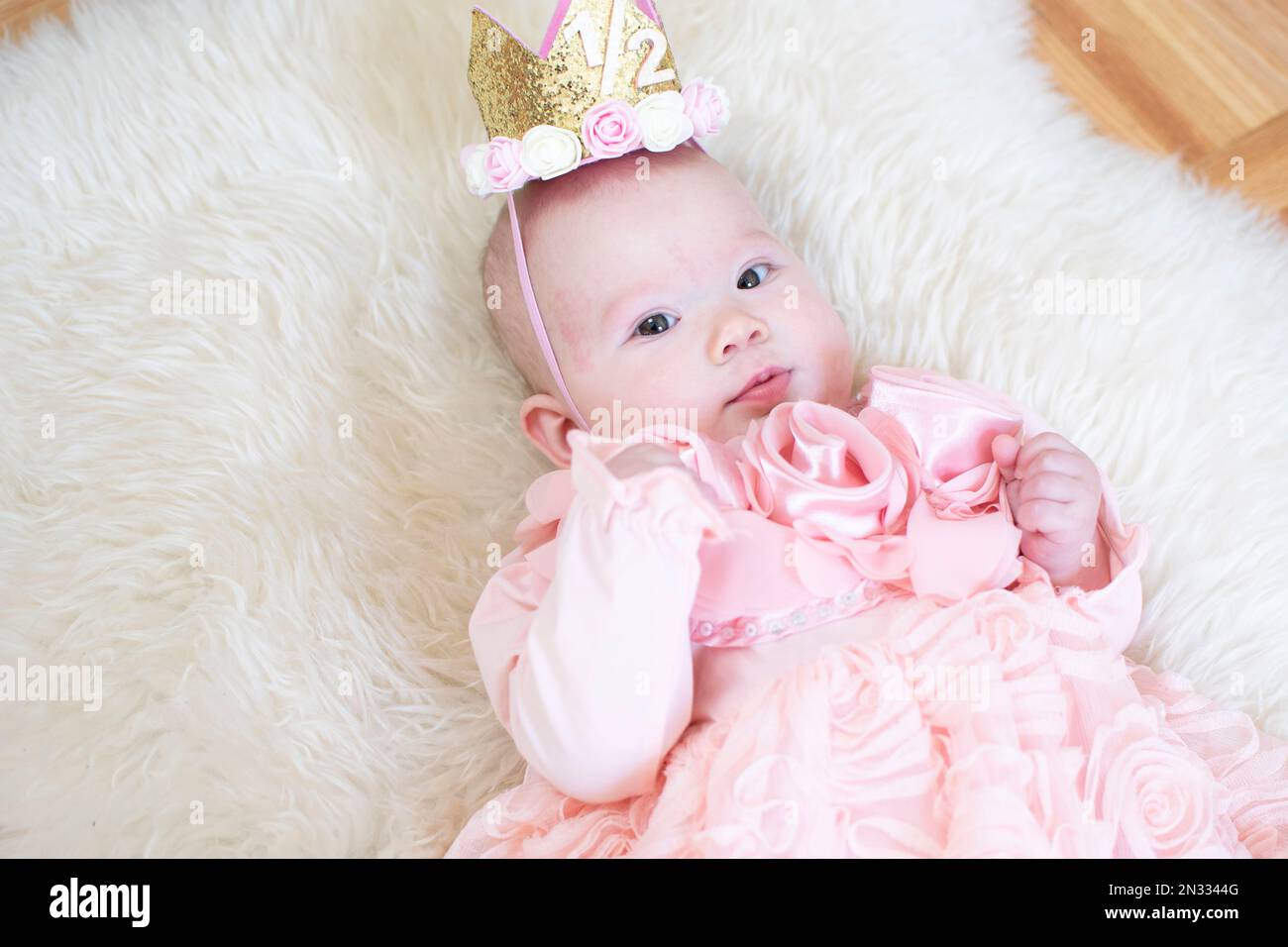 6 Monate altes Mädchen. Halbjahr. Alles gute zum Geburtstag, Prinzessin. Süßes, weißes Mädchen in einem rosa Kleid. Diadem-Baby Stockfoto