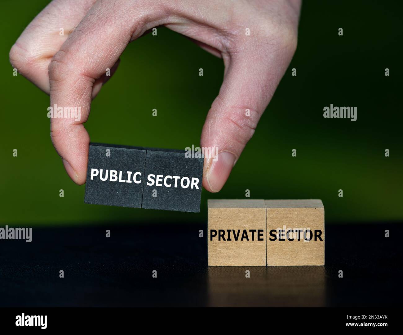 Mit der Hand werden Würfel mit dem Ausdruck „öffentlicher Sektor“ anstelle von Würfel mit dem Text „privater Sektor“ ausgewählt. Stockfoto