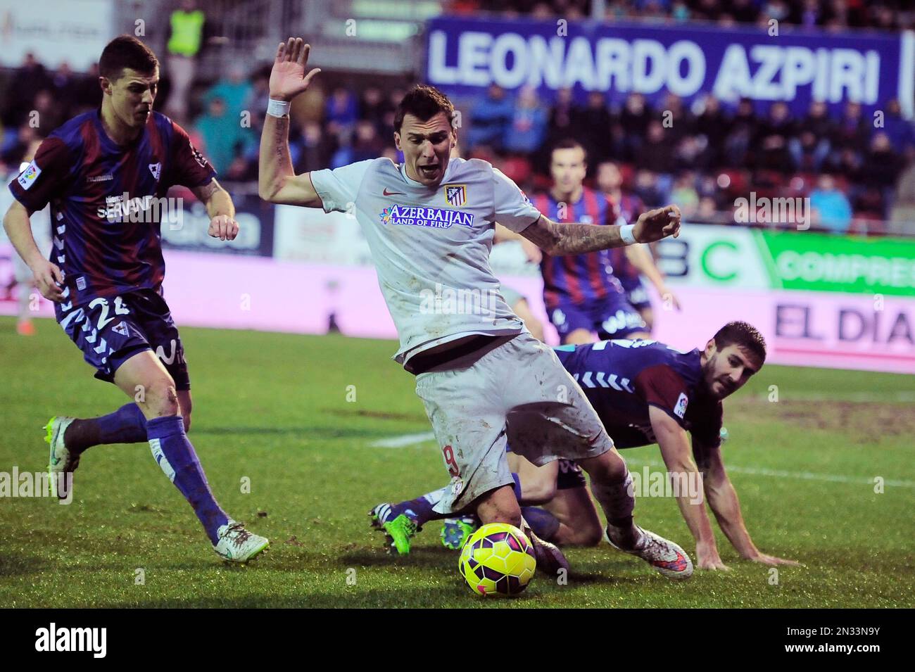 Atletico de Madrid's Mario Mandzukic, center, is tackled by SD Eibar's Eneko Boveda, right, during their La Liga soccer match, at Ipurua stadium in Eibar, northern Spain, Saturday, Jan. 31, 2015. (AP Photo/Alvaro Barrientos) Stockfoto
