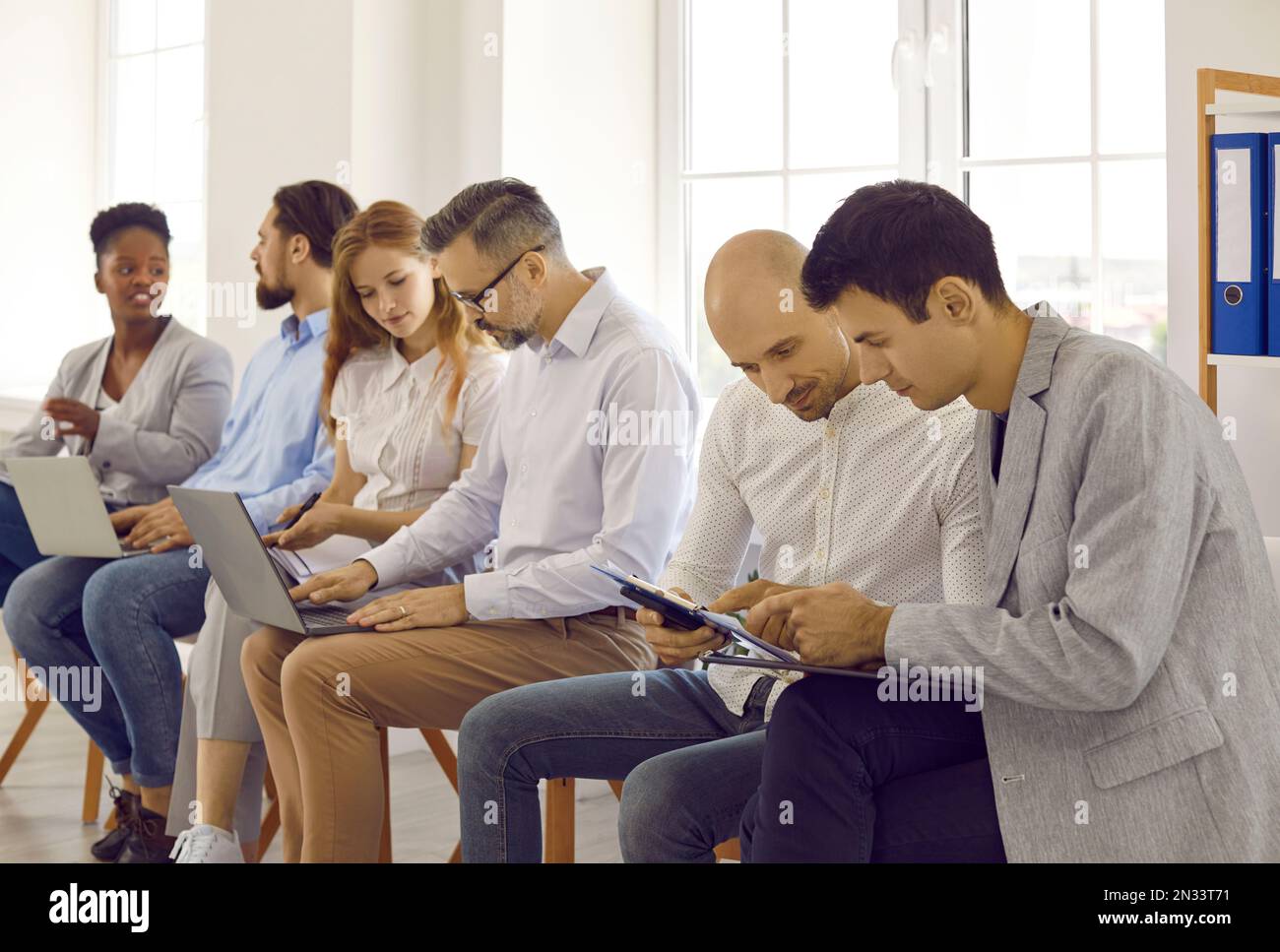 Geschäftsleute, die an Seminarschulungen teilnehmen und in Paaren diskutieren, um Aufgaben mithilfe von Laptops gemeinsam zu erledigen. Stockfoto