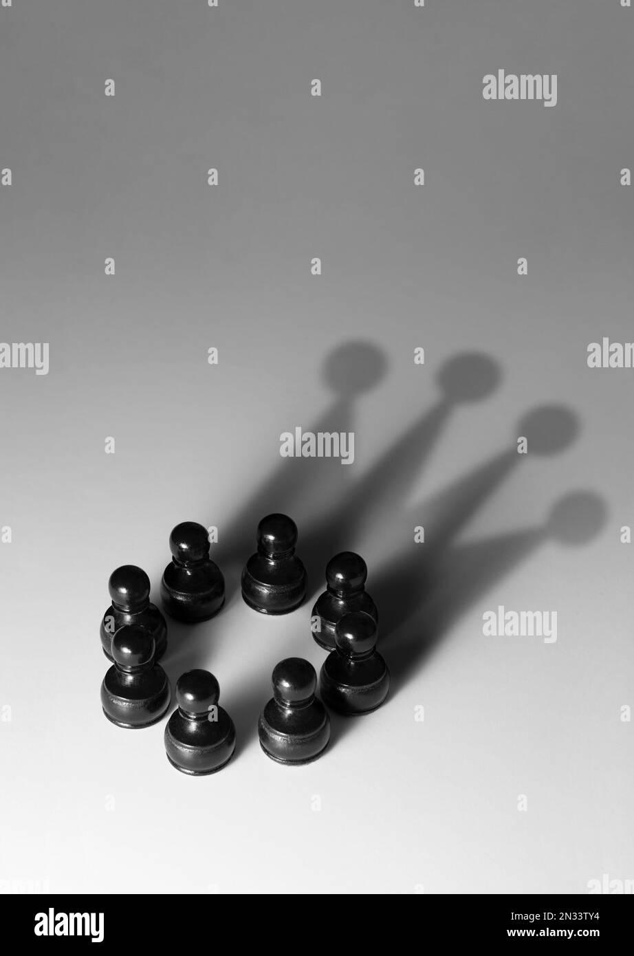 Eine Gruppe schwarzer Bauern mit einem Schatten, der als Krone geformt ist Stockfoto