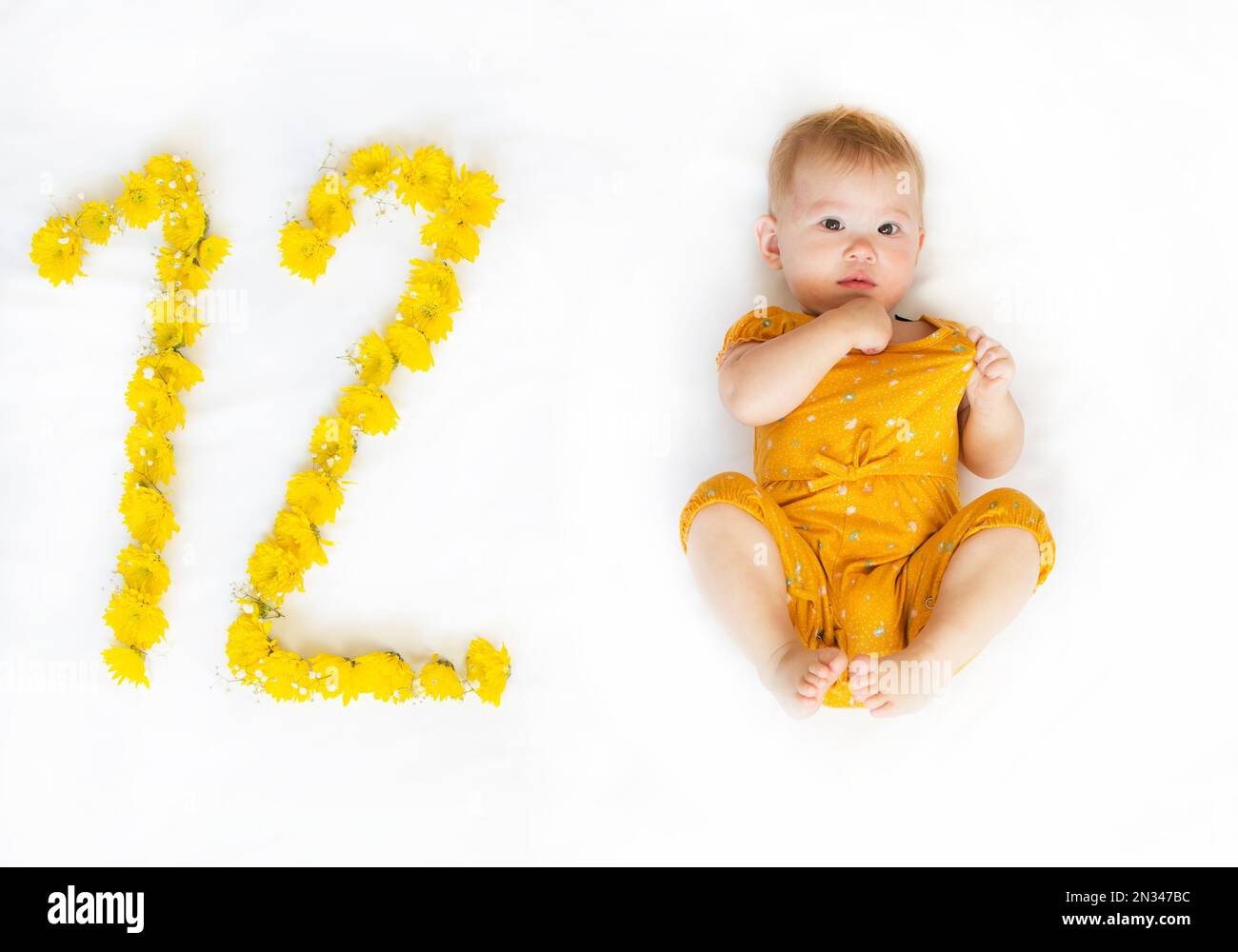 12 Monate altes Mädchen in gelbem Outfit. Erster Geburtstag Stockfoto