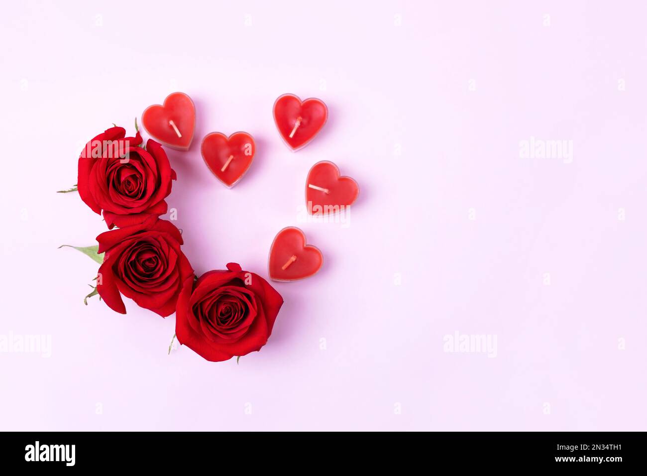 Romantischer Hintergrund mit Platz für Text. Rote Rosen und Kerzen in Herzform. Valentinstag-Konzept. Flach verlegt Stockfoto