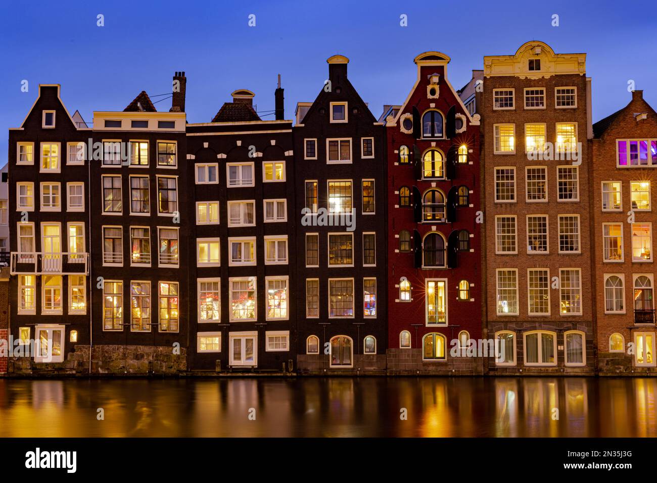 Amsterdam, Niederlande - 18. Januar 2023: Stadtbild traditioneller holländischer Häuser bei Sonnenuntergang am Damrak-Kanal in Amsterdam Stockfoto