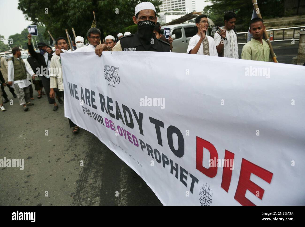 Indonesian Muslim protesters hold a banner that reads "We are ready to die for our beloved Prophet" during a protest against caricatures published in French magazine Charlie Hebdo, in Jakarta, Indonesia, Friday, Jan. 23, 2015. Around 100 people staged a protest against the publishers of the French satirical magazine, accusing them of blasphemy. (AP Photo/Achmad Ibrahim) Stockfoto