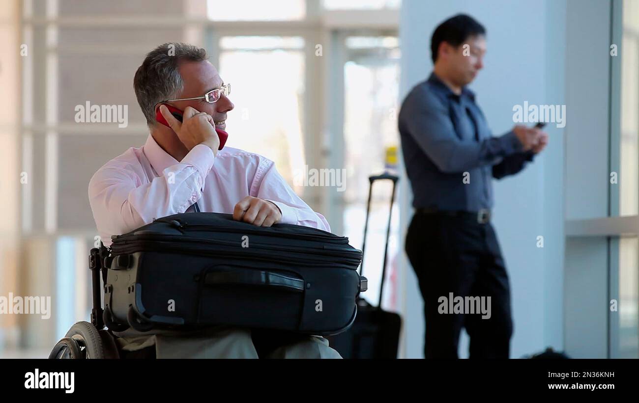 Mann im rollstuhl rollt mit gepäck und rucksack auf dem rücken an der  sicherheitskontrolle am flughafen vorbei