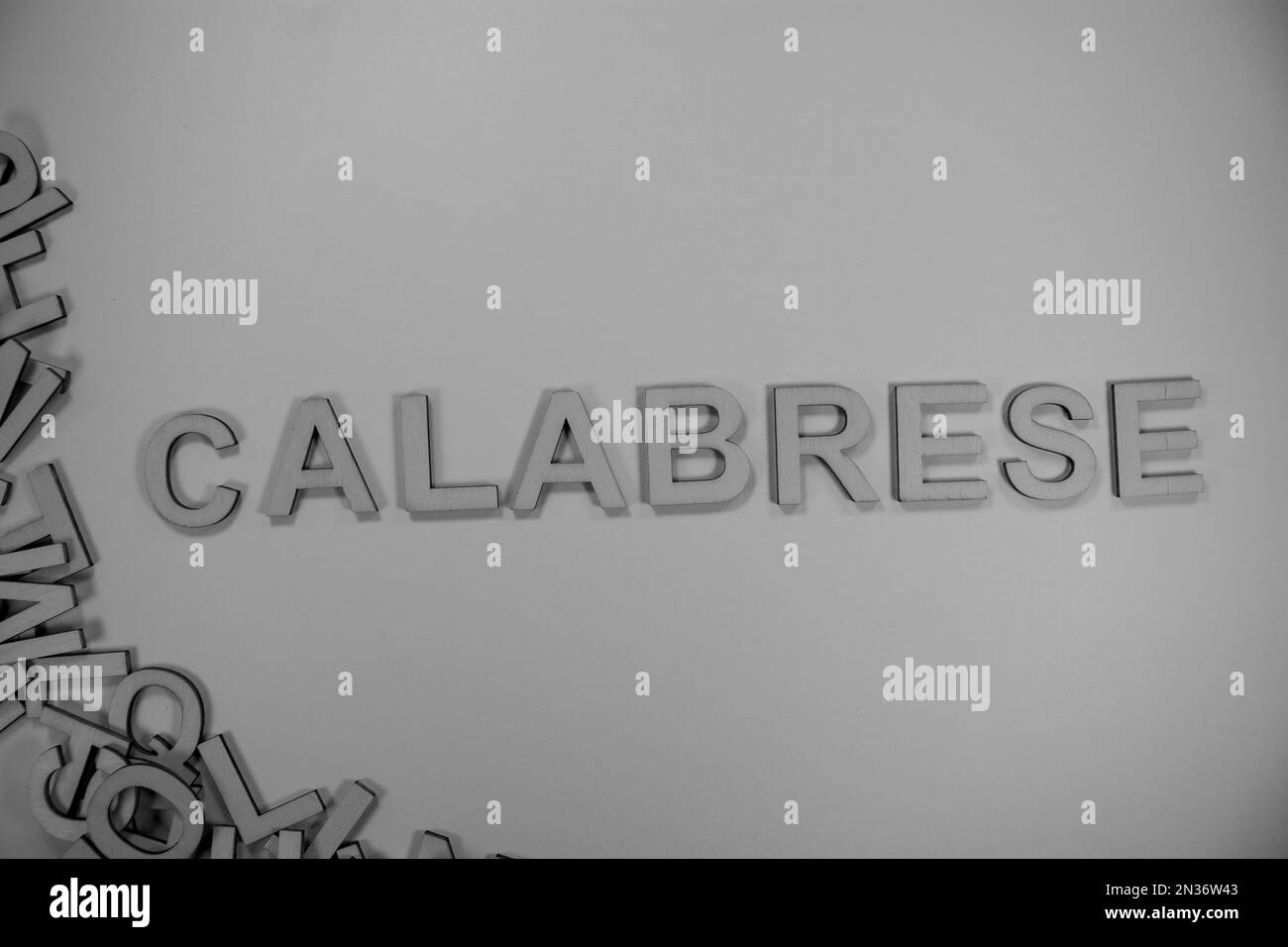 CALABRESE in hölzernen englischen Wörtern, Großbuchstaben, die aus einem Stapel schwarz-weißer Buchstaben herausfließen Stockfoto