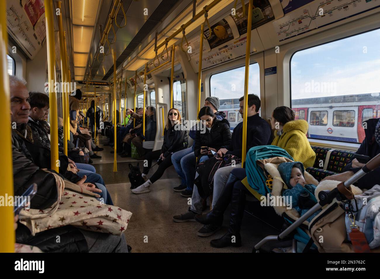 Familien fahren am Wochenende in einer geschäftigen Zugfahrt der Londoner U-Bahn District Line im Zentrum von London, England, Großbritannien Stockfoto