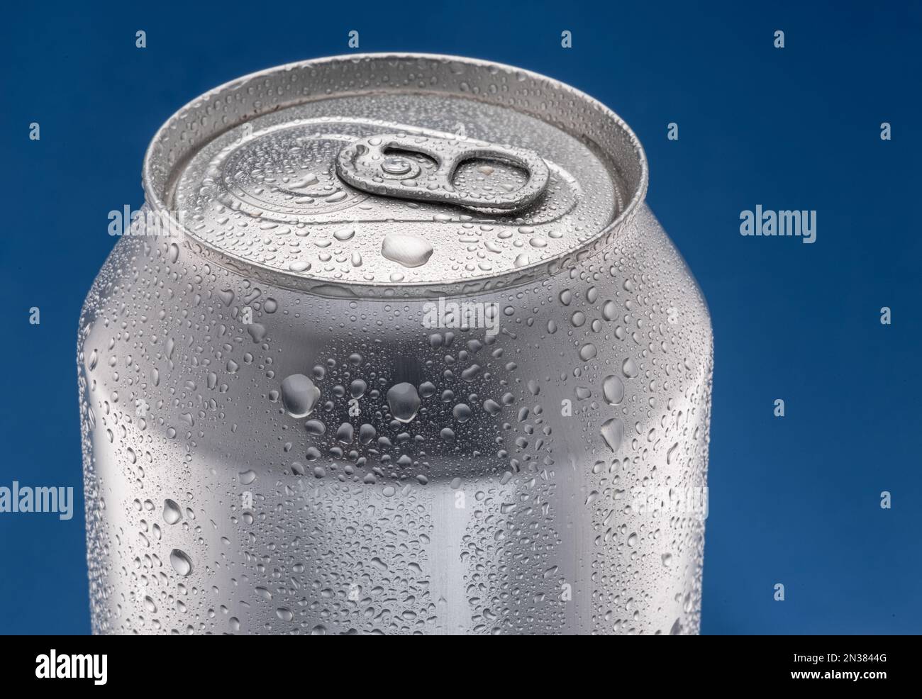 Gekühltes Silberbier mit Kondensation auf blauem Hintergrund bedeckt. Stockfoto