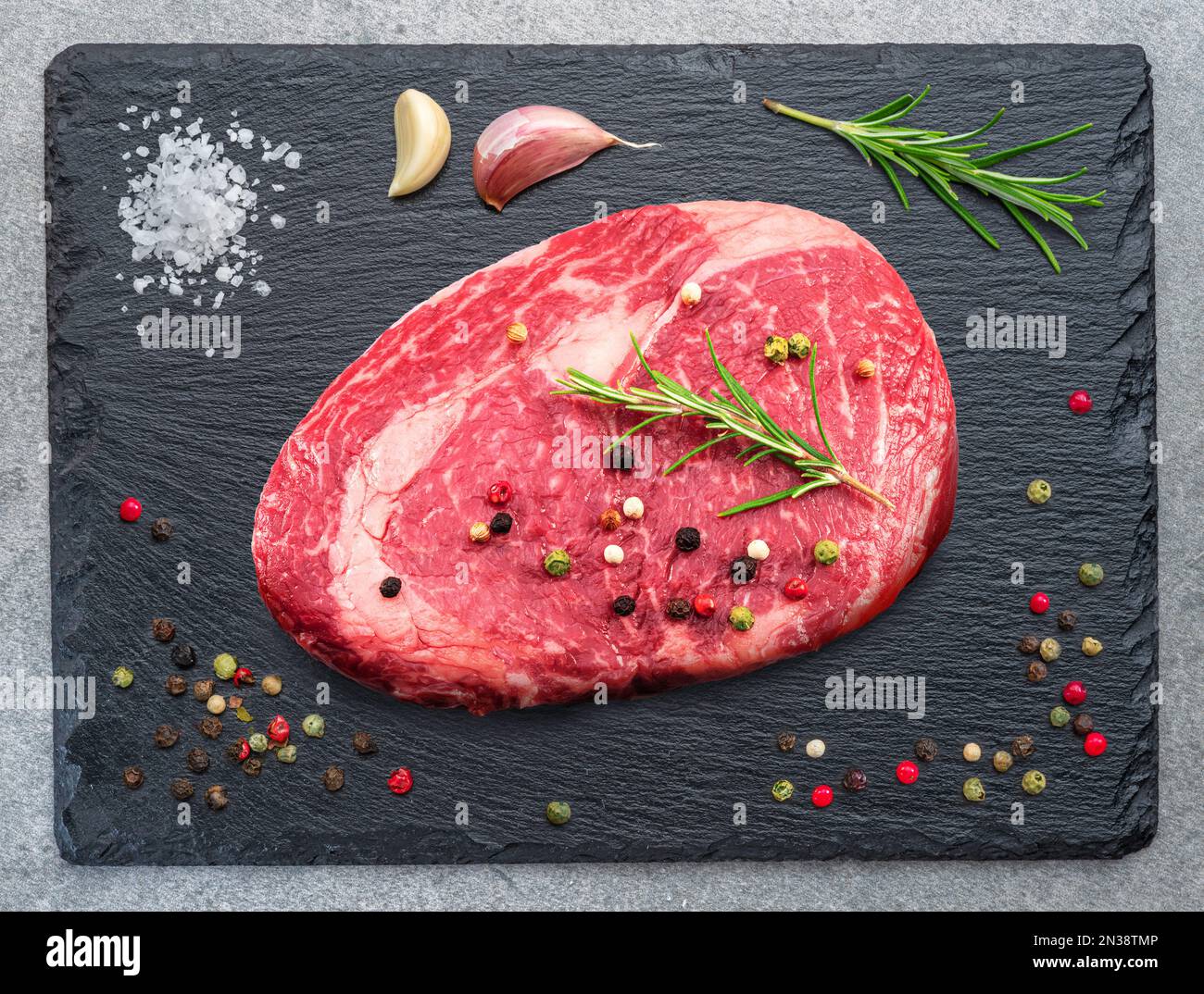 Rohes Ribeye Steak auf steinschwarzem Servierteller. Flach verlegt. Stockfoto