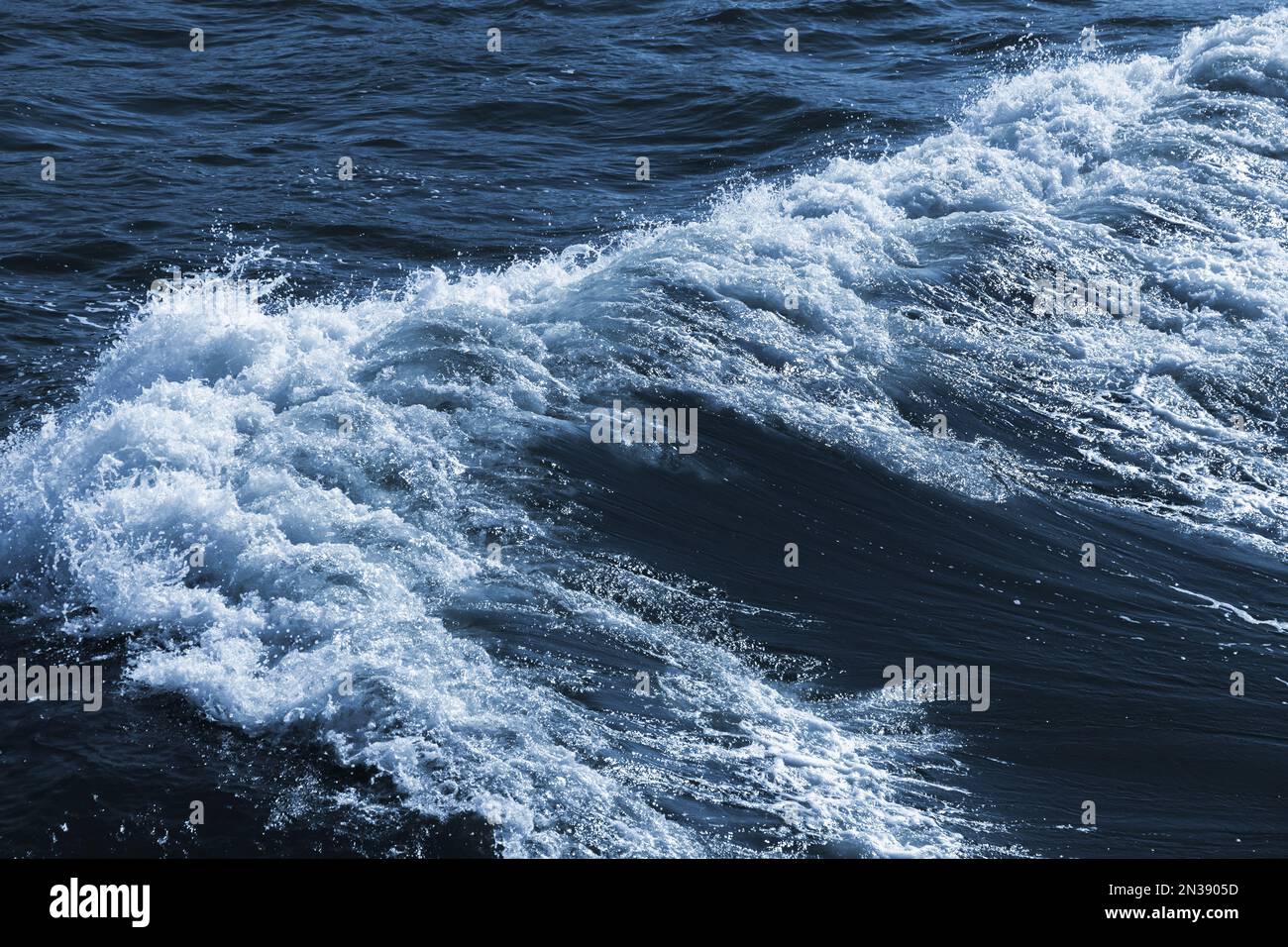 Meereswelle mit weißem Schaum auf tiefblauem Wasser, natürliches Hintergrundfoto Stockfoto