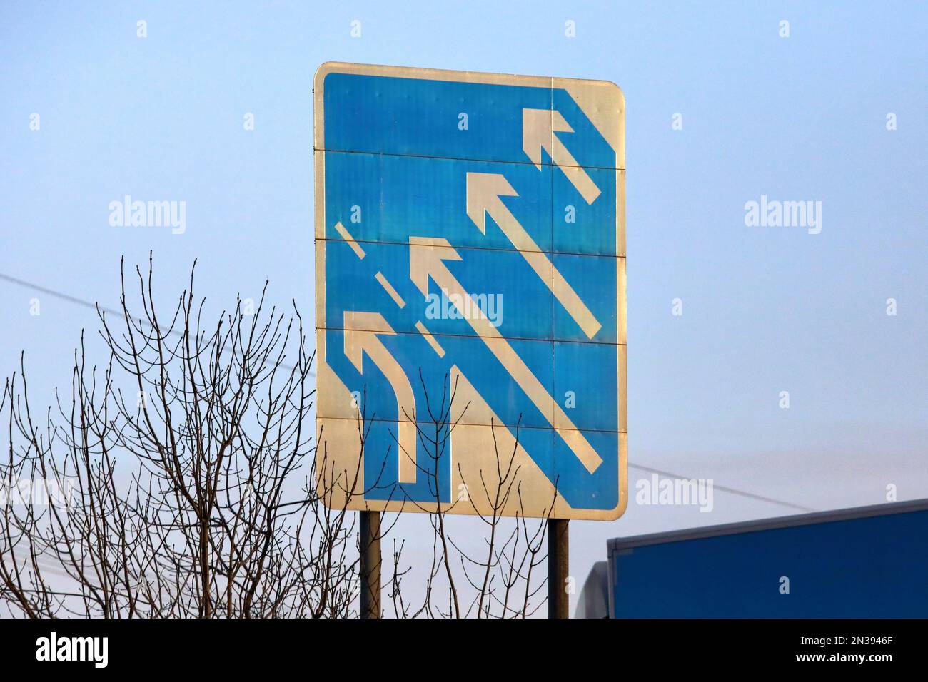 Autobahnschild, das darauf hinweist, dass die Zufahrtsstraße als Spurversatz auf die Hauptstraße trifft, um die Anzahl der Fahrspuren von drei auf vier zu erhöhen Stockfoto